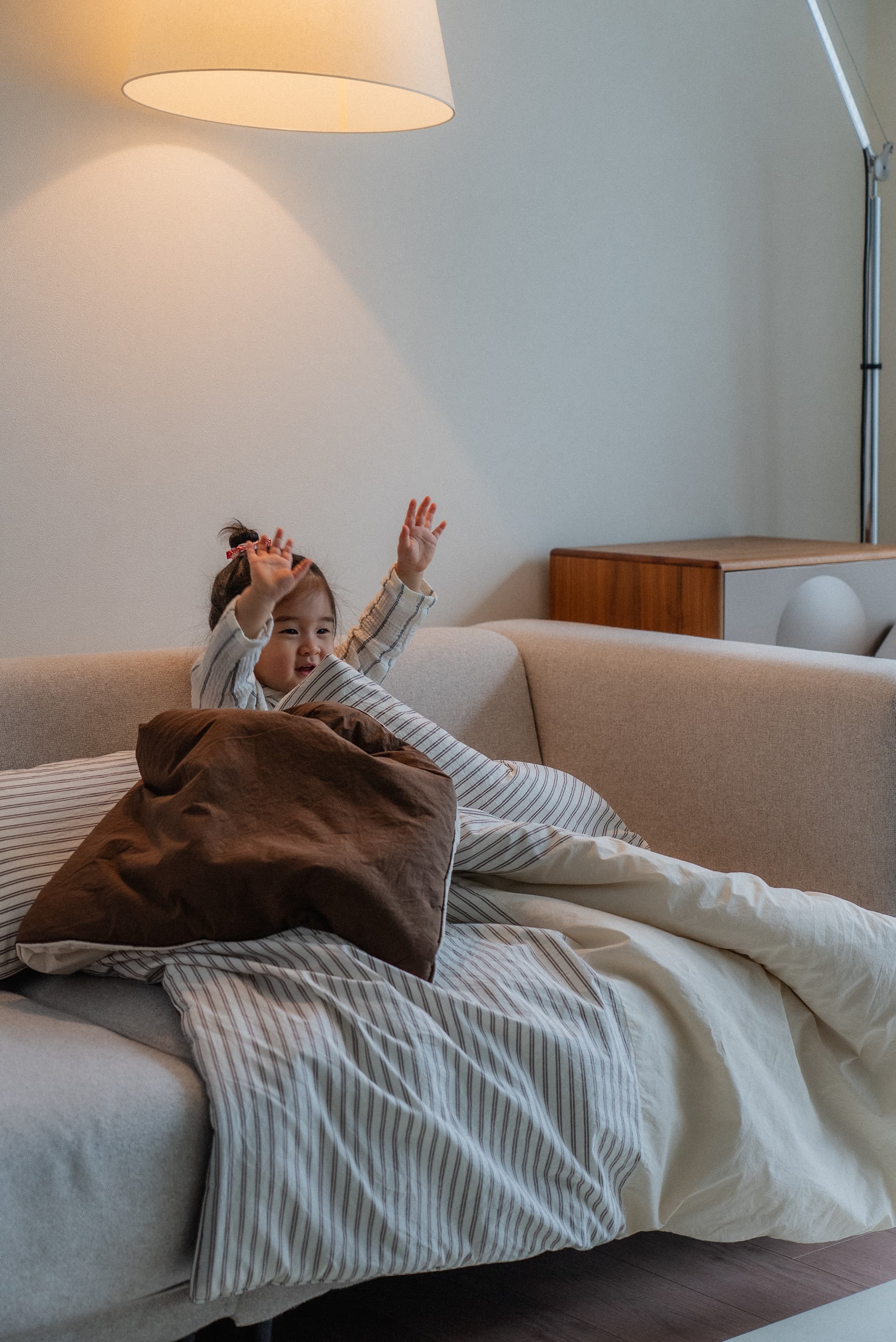 Child sitting on a soft white bed playing with toys