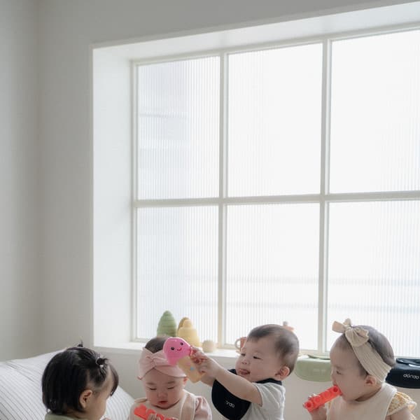 Child sitting on a soft white bed playing with toys
